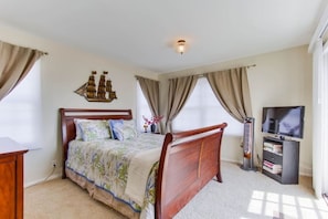 A bedroom with a wooden bed, a television, and a ship decoration on the wall. - Oceanview from rooftop patio, parking, bikes, pets (San Diego)