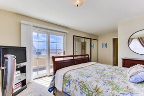 A hotel room with a bed, a television, a heater, a wardrobe, and a sliding glass door leading to a balcony.
