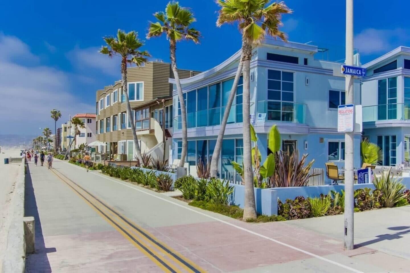 Un hôtel situé en bord de mer, doté d’un design moderne, d’une promenade et de palmiers.