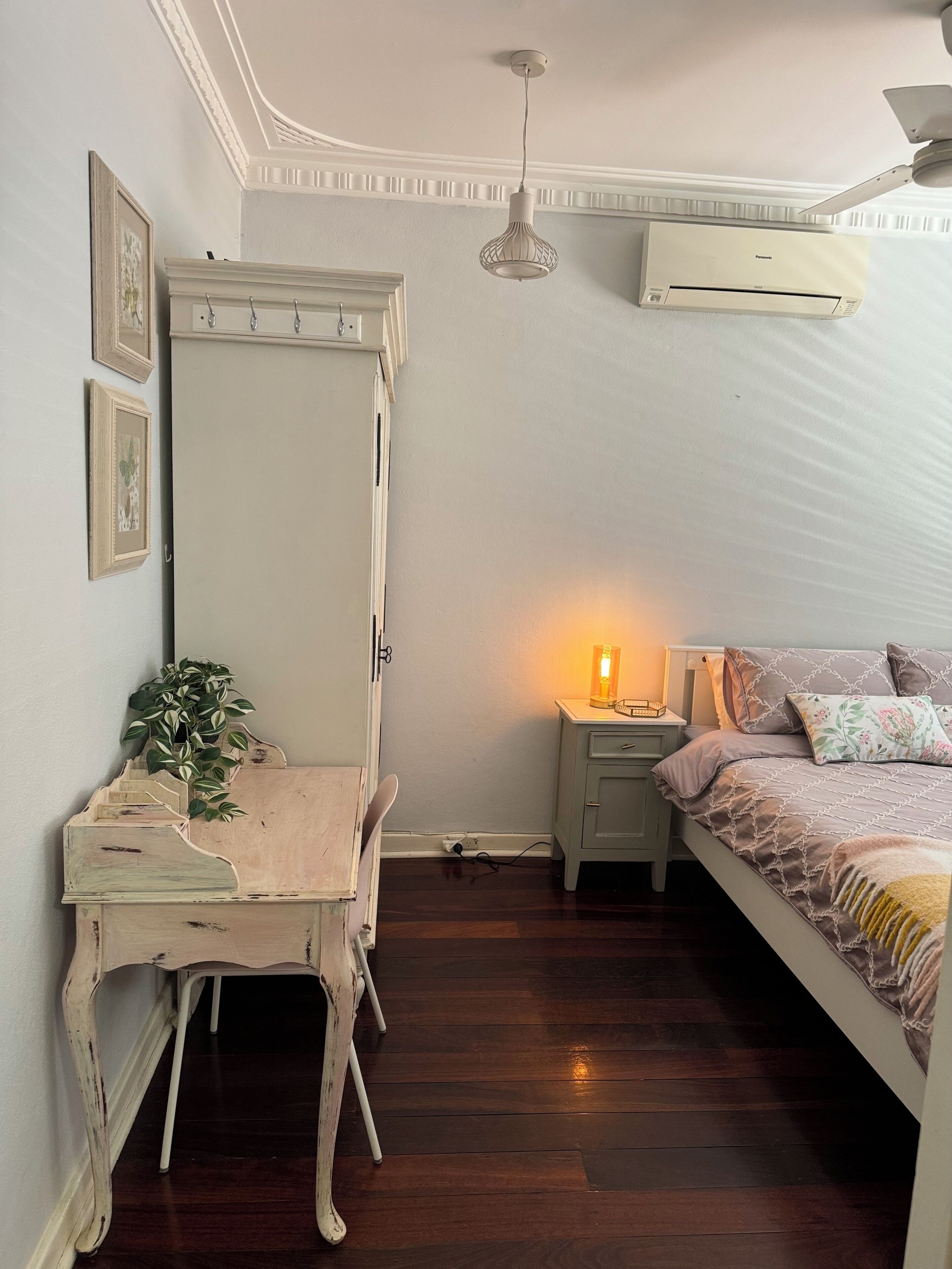 A bedroom with a bed, a nightstand, a dresser, a lamp, and an air conditioner.