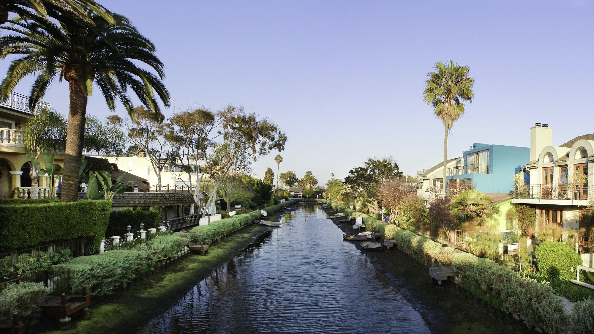 Un canal flanqueado por palmeras y setos cuidados, con edificios a ambos lados.