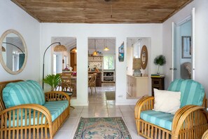 A room with wicker furniture, a mirror, and a view into the kitchen. - Poponi Villa on pink sand Beachfront Estate (North Palmetto Point)