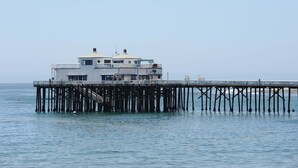 A pier with a building at the end, featuring a staircase and a viewing platform. - Oceanfront Cottage on Carbon Beach -Sea Lion (Malibu)