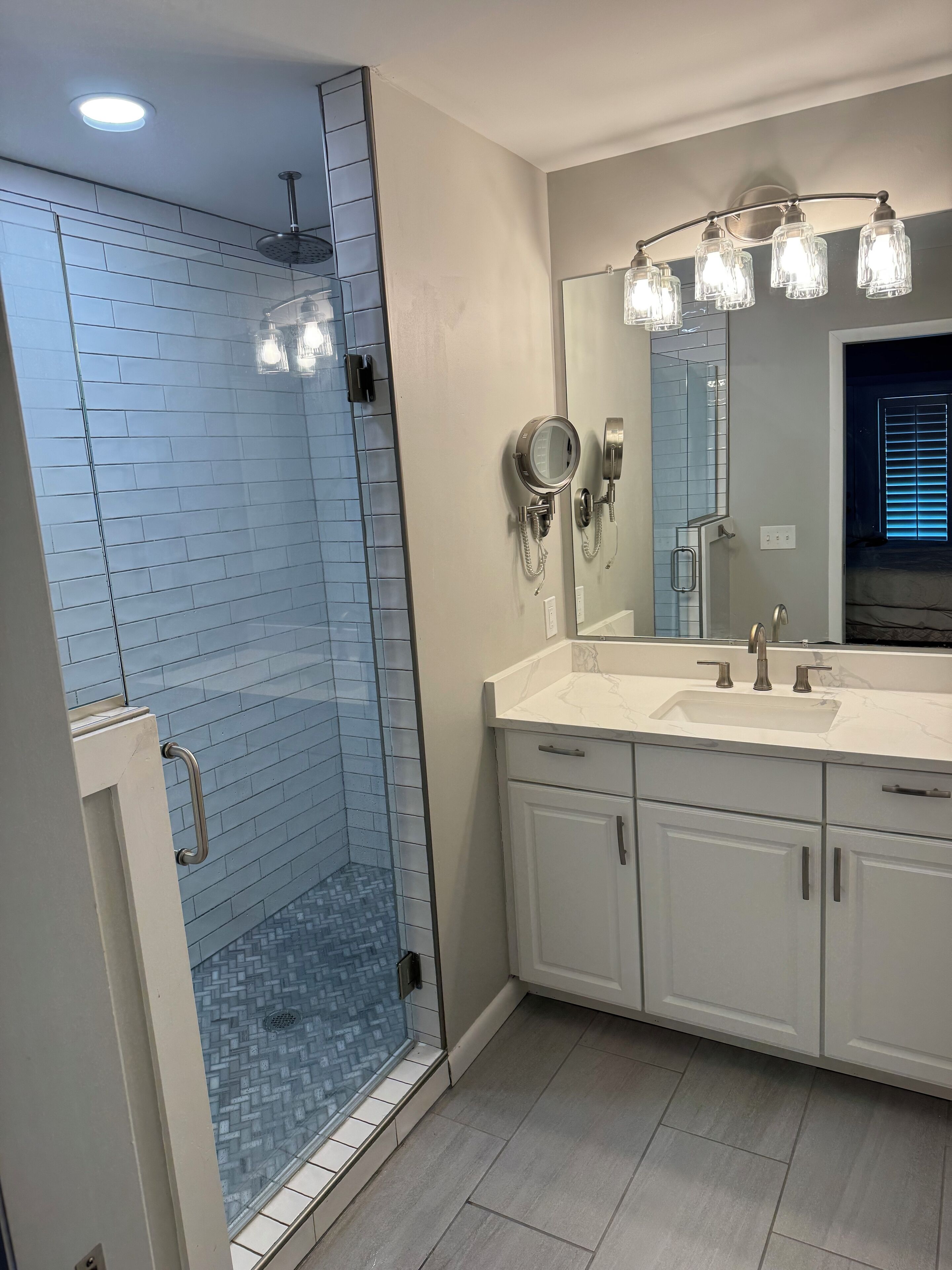 A modern bathroom with a glass-enclosed shower, a vanity with a mirror, and a sink.