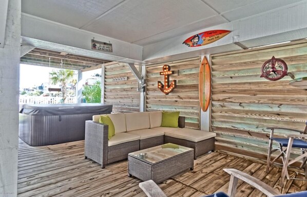 A cozy lounge area with a sectional sofa, a small table, and a surfboard decoration on the wall.