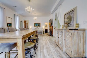 Ein großzügiger Essbereich mit einem langen Holztisch, mehreren Stühlen, einer Chandelierleuchtre und einem dekorativen Schrank mit einer Uhr.