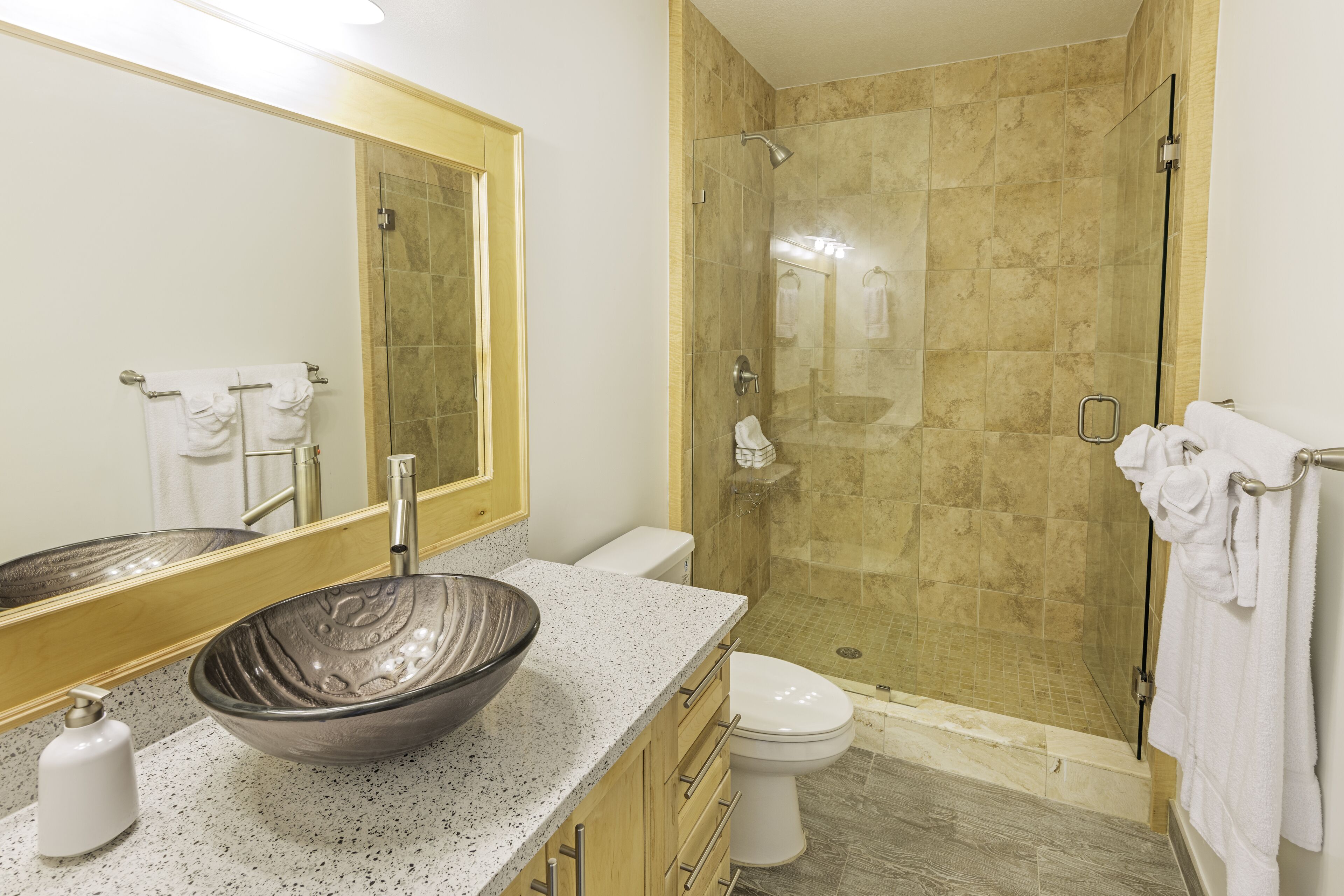 Une salle de bain moderne avec un grand miroir, un lavabo sur colonne, des toilettes et une douche à parois de verre.