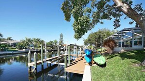 Un port de plaisance avec des quais en bois s’étendant dans une eau calme, entouré d’une végétation luxuriante et de bâtiments résidentiels.