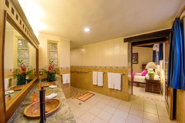 A bathroom with a large mirror, a wooden basin, a towel rack, and a shower area.