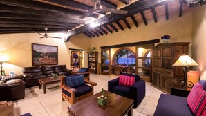 Un'accogliente area relax con divani in pelle, tavoli in legno e una ventola a soffitto.