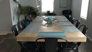 Een eetkamer met een lange houten tafel, zwarte stoelen en een decoratieve schaal als middelpunt.