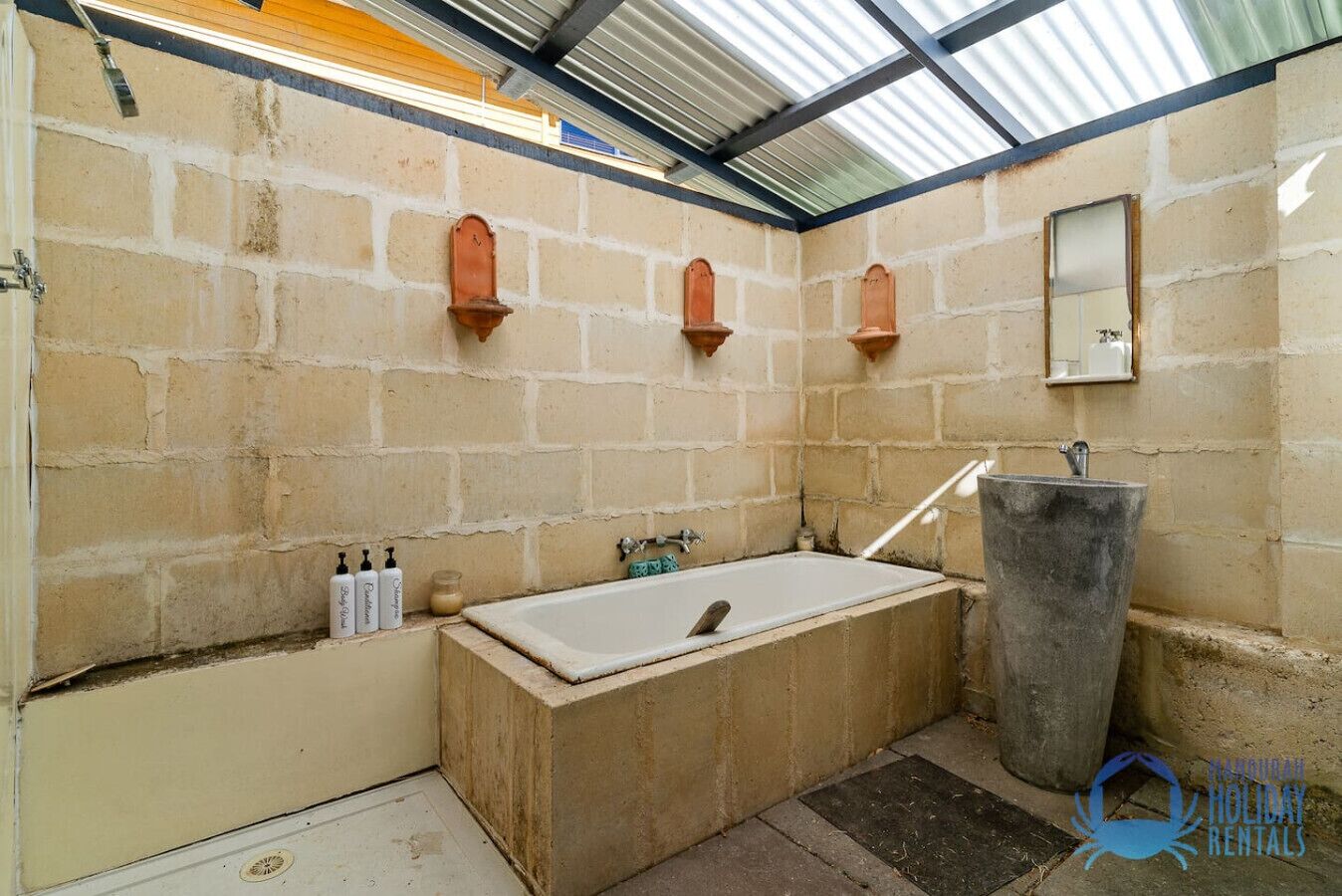 Une salle de bain avec une baignoire, un lavabo et un miroir. On y trouve des articles de toilette accrochés au mur.