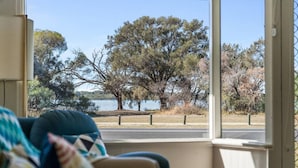 A view from a window overlooking a lake with trees and a grassy area.