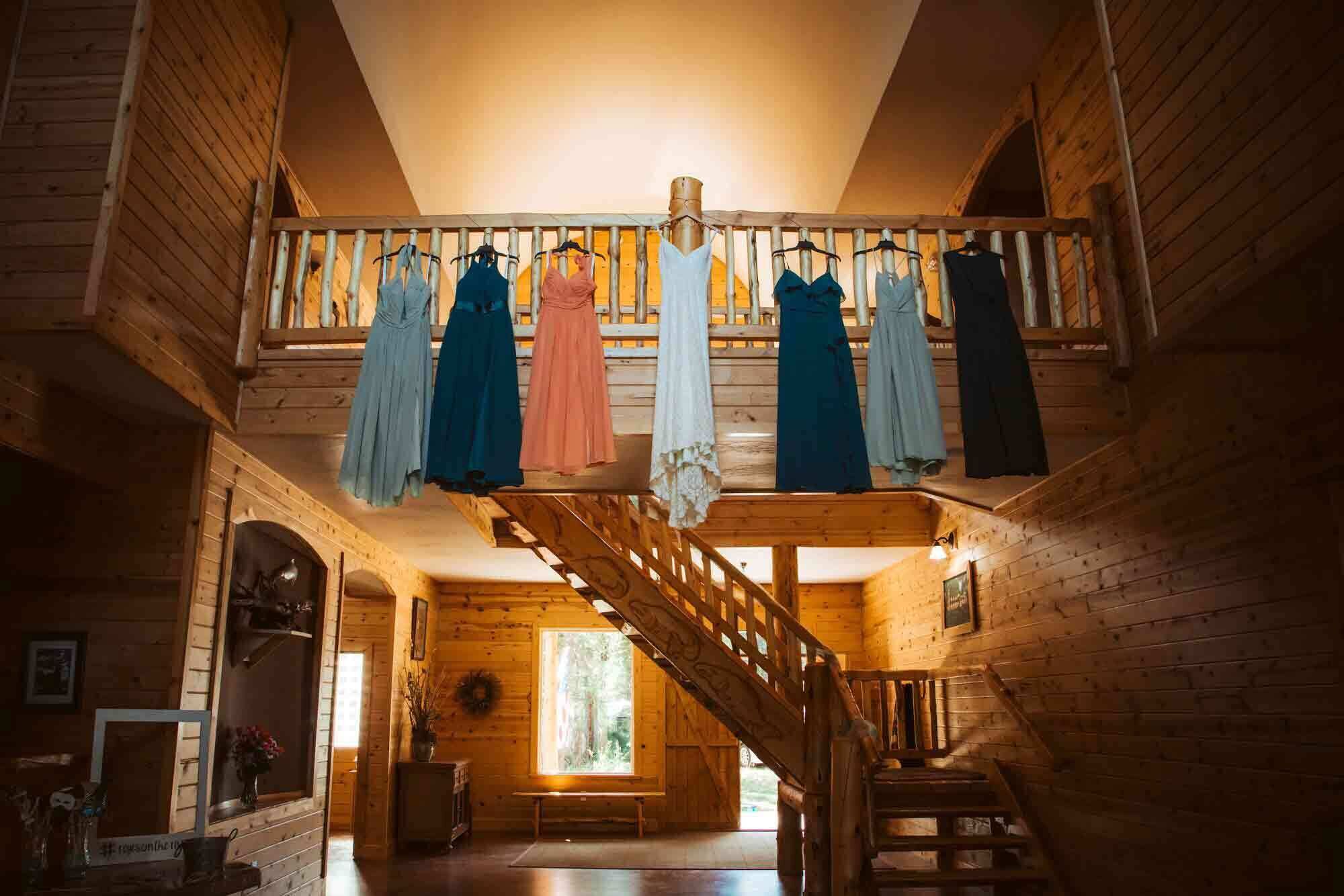 Un intérieur en bois avec un escalier menant à un balcon où sont suspendues des robes.