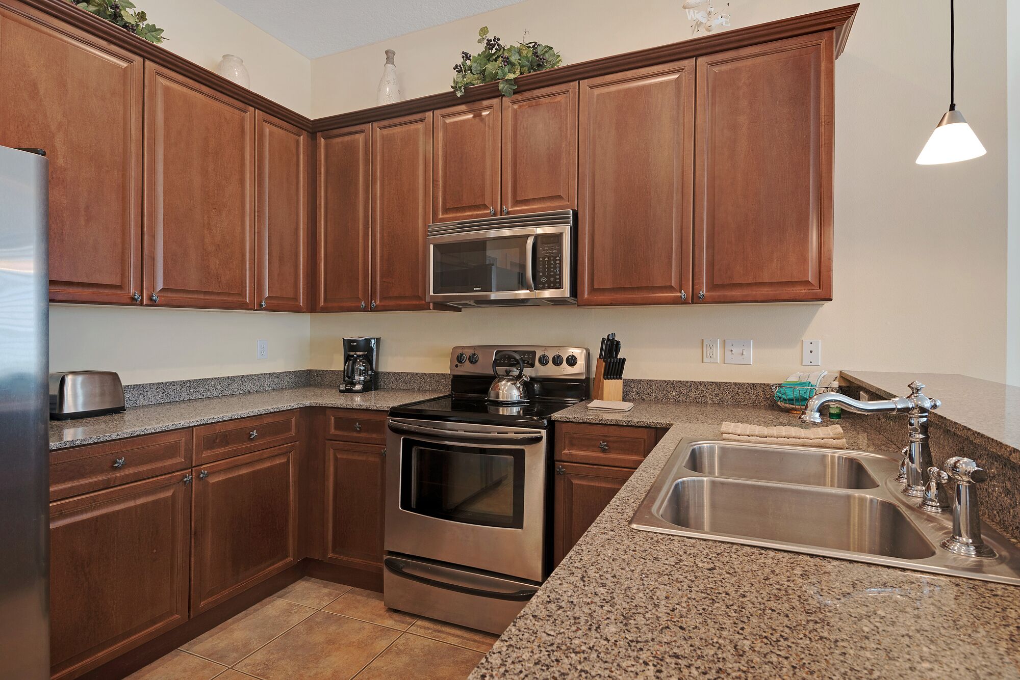 A kitchen with wooden cabinets, stainless steel appliances, granite countertops, and a sink.
