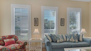 A living room with a floral sofa, a blue sofa with patterned cushions, a glass coffee table, and white lamps. - The fun begins at the Flip Flop Inn! - FREE Beach Serv-In Season- 4 min to Gulf! (Miramar Beach)