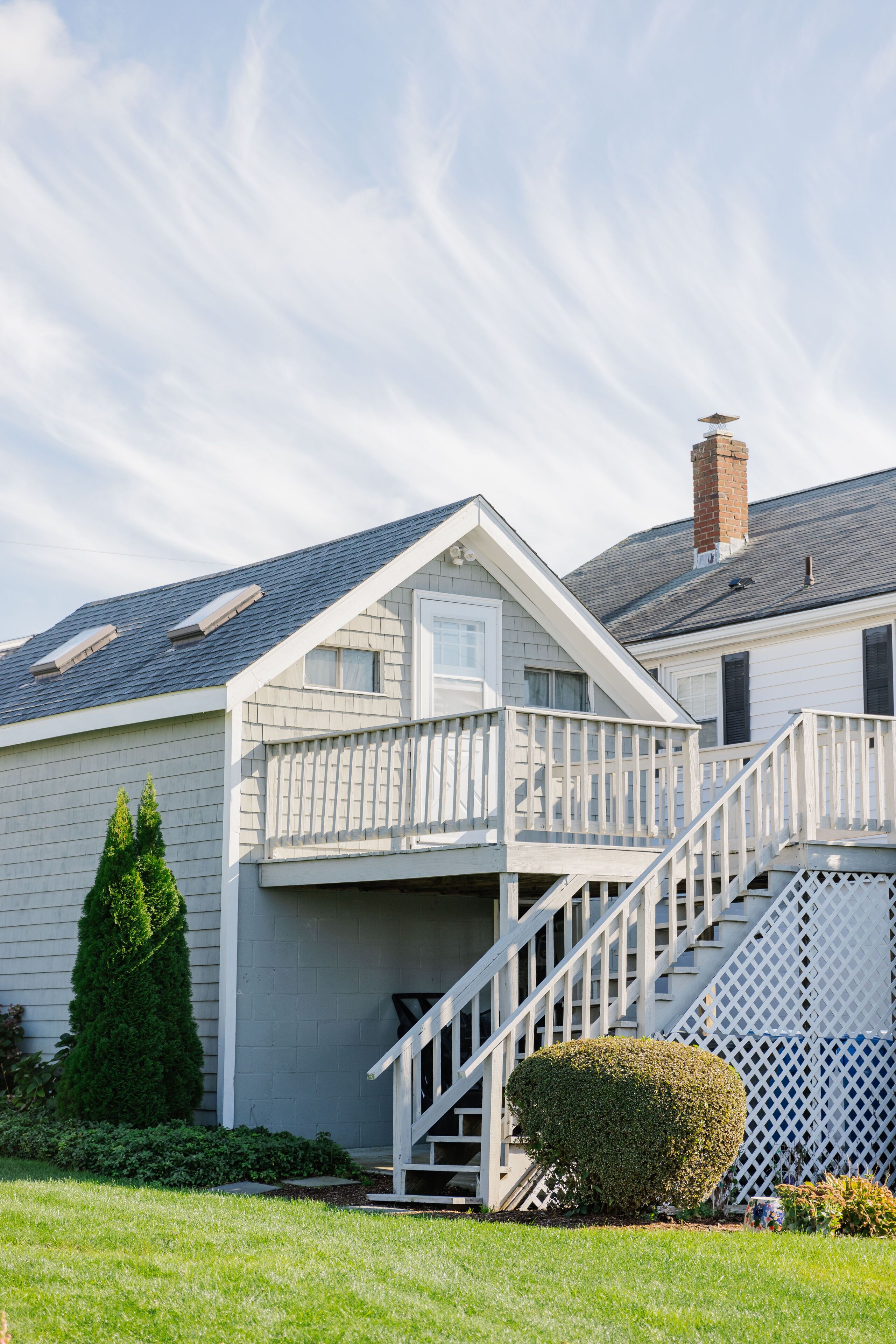A two-story house with a white exterior, a front porch, and a staircase leading to the second floor.