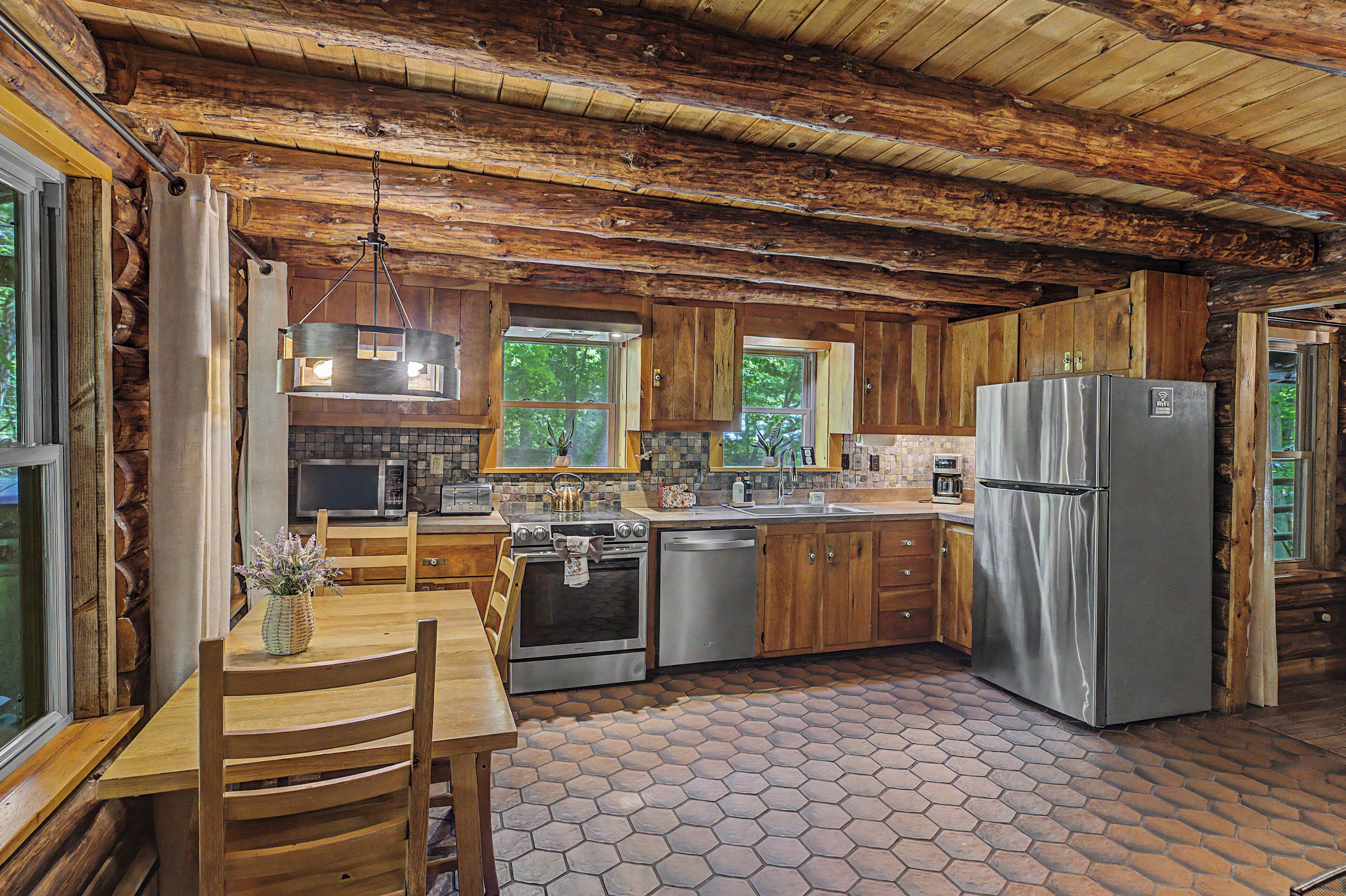 A rustic kitchen with wooden cabinets, a stainless steel refrigerator, and a hexagonal tile floor.