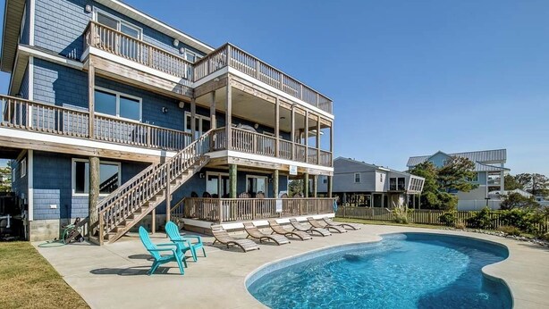 A multi-story building with a swimming pool, outdoor seating, and a staircase leading to a balcony. - Down South | 450 ft from the beach | Private Pool (Virginia Beach)