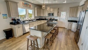 A spacious kitchen with a large island, wooden stools, and modern appliances. - Down South | 450 ft from the beach | Private Pool (Virginia Beach)