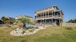 A multi-story residential building with a pool, surrounded by a landscaped garden and a wooden fence. - Down South | 450 ft from the beach | Private Pool (Virginia Beach)