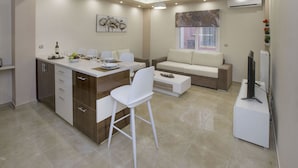 A modern kitchen with a dining area, featuring a white sofa, a dining table, and a TV. - Spacious & Convenient Place near Acropolis Museum by GHH (Athens)