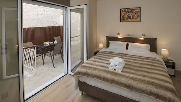 A hotel room with a bed, a balcony with a table and chairs, and a painting on the wall. - Spacious & Convenient Place near Acropolis Museum by GHH (Athens)