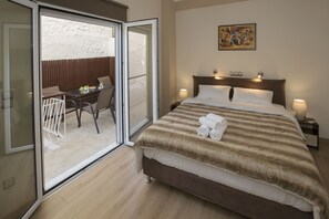 A hotel room with a bed, a balcony with a table and chairs, and a painting on the wall. - Spacious & Convenient Place near Acropolis Museum by GHH (Athens)