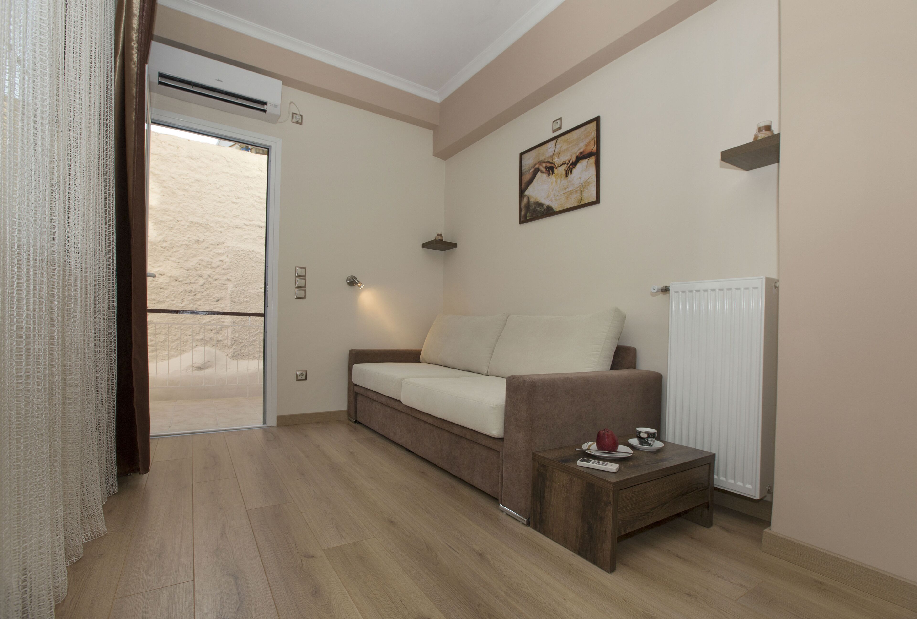 A room with a sofa, a small table, a radiator, and a picture on the wall.