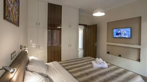 A hotel room with a bed, a TV mounted on the wall, and a wardrobe. - Spacious & Convenient Place near Acropolis Museum by GHH (Athens)