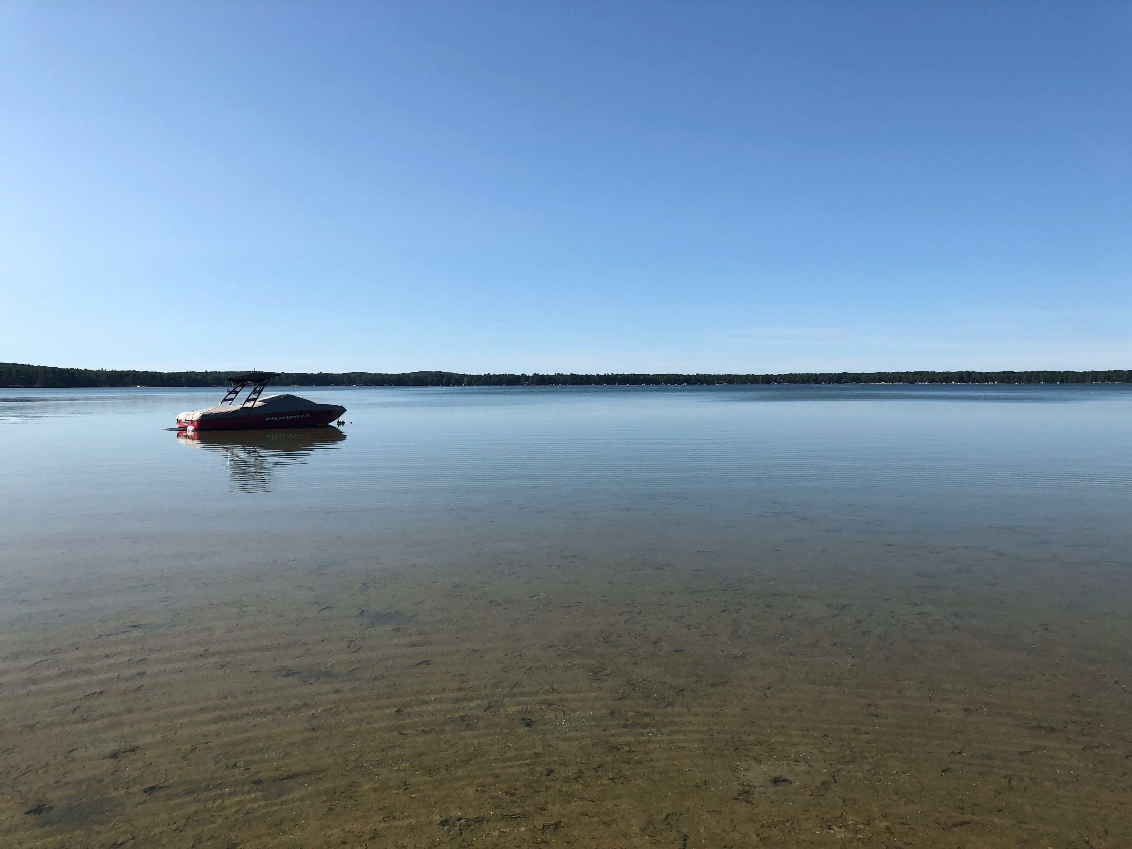 A boat on a calm lake with a clear sky.