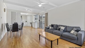 A modern living room with a grey sofa, wooden coffee table, and dining area with chairs. - Room for the whole family (Eildon)