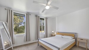 A bedroom with a bed, a ceiling fan, and two windows with curtains. - Room for the whole family (Eildon)