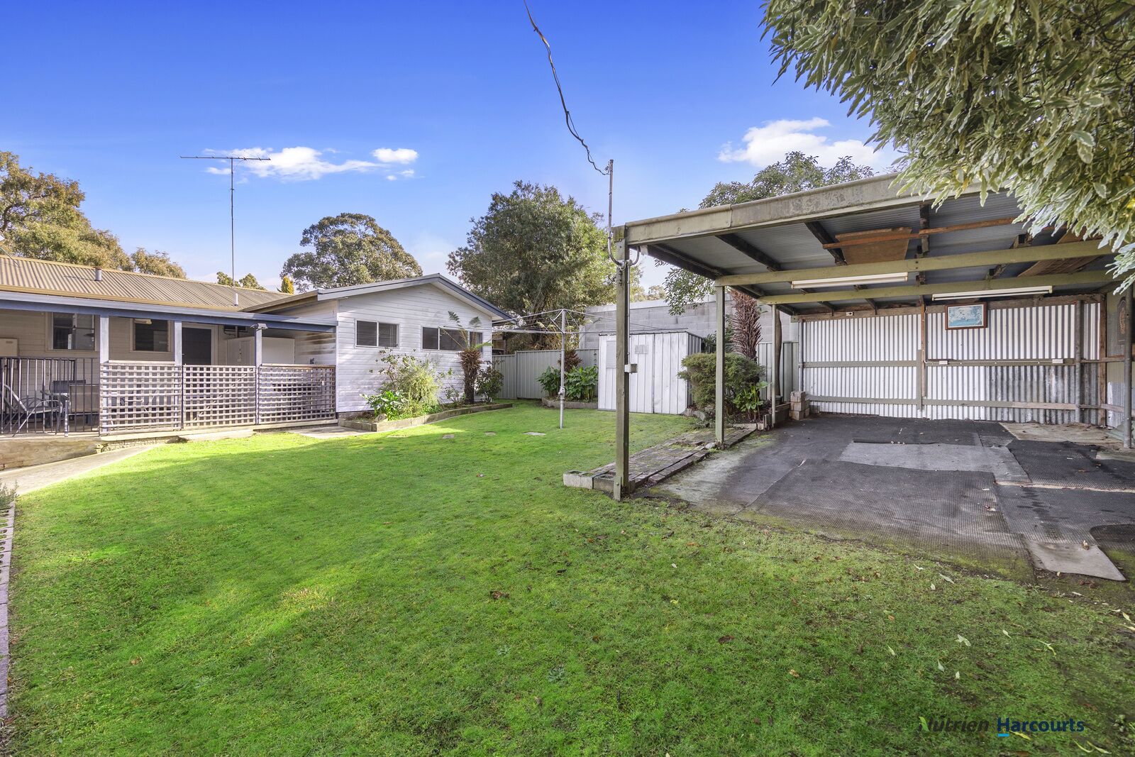 A residential backyard with a covered patio, a fenced area, and a house with a garage.