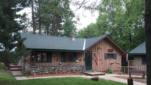 A rustic lodge with a stone foundation, wooden exterior, and a green roof.