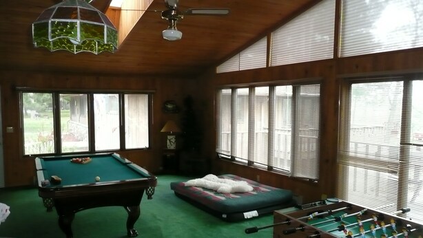A room with a pool table, a foosball table, and a sofa.