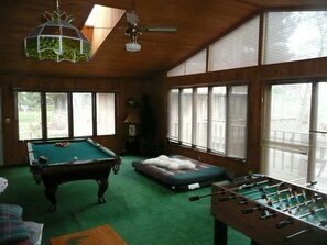 Una habitación con mesa de billar, mesa de futbolín y sofá.