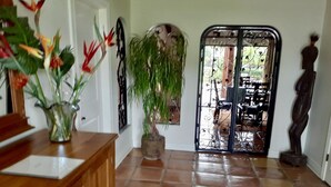 A hallway with a tiled floor, a wooden counter, a potted plant, a decorative metal gate, and a statue.