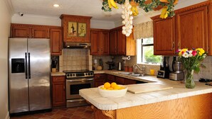 A kitchen with wooden cabinets, stainless steel appliances, and a fruit basket hanging from the ceiling.