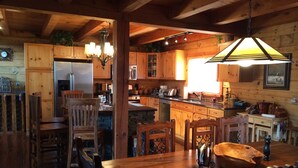 Un interior rústico de madera con comedor, cocina y una araña.