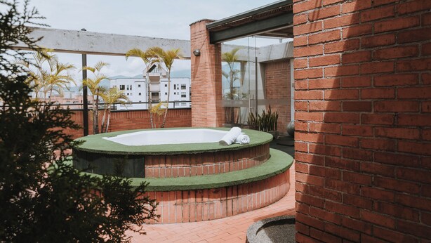 Uma piscina no terraço, com parede de tijolos e janelas de vidro.