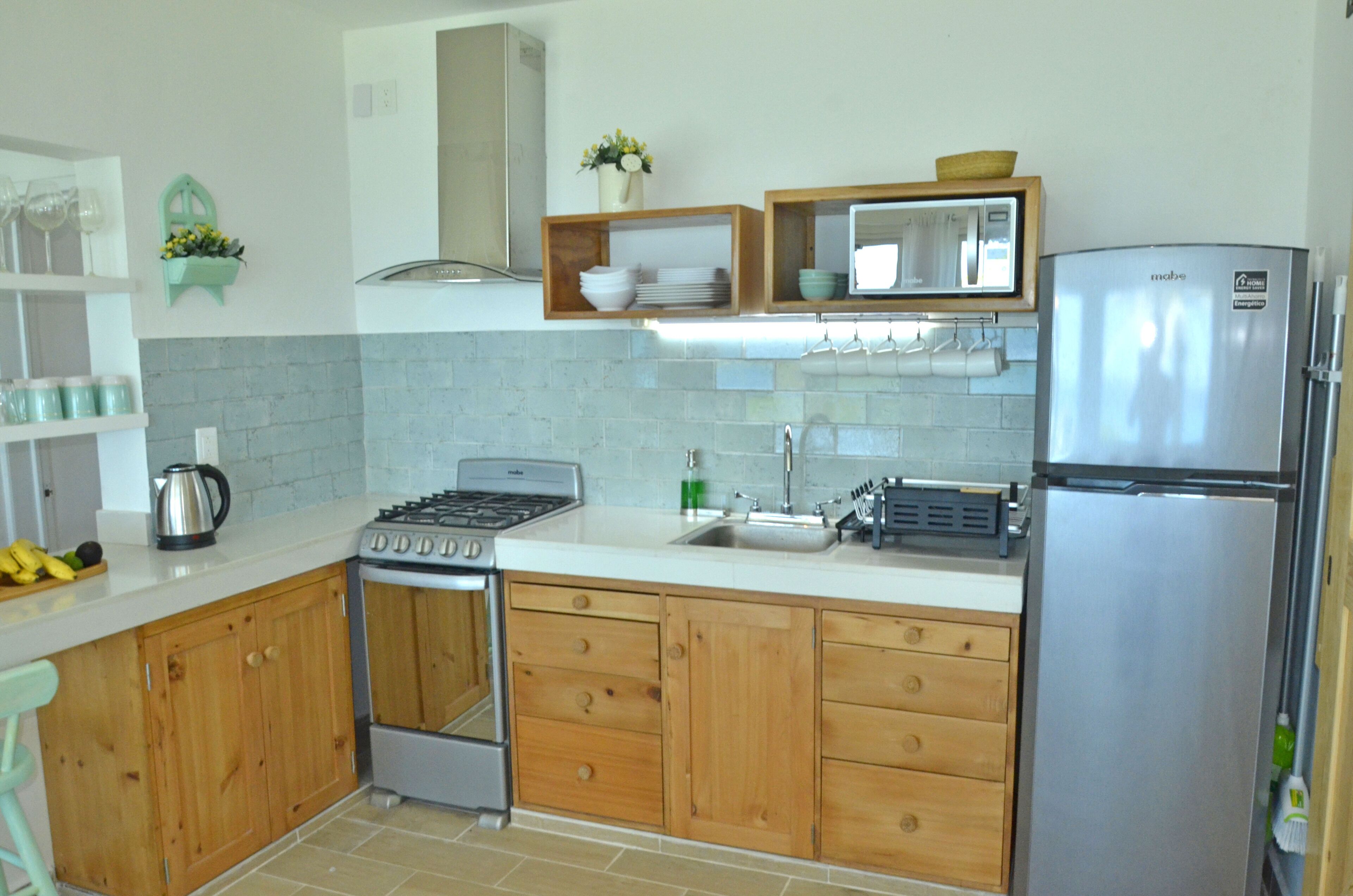 Una cocina con gabinetes de madera, un refrigerador de acero inoxidable, una estufa y un lavamanos.