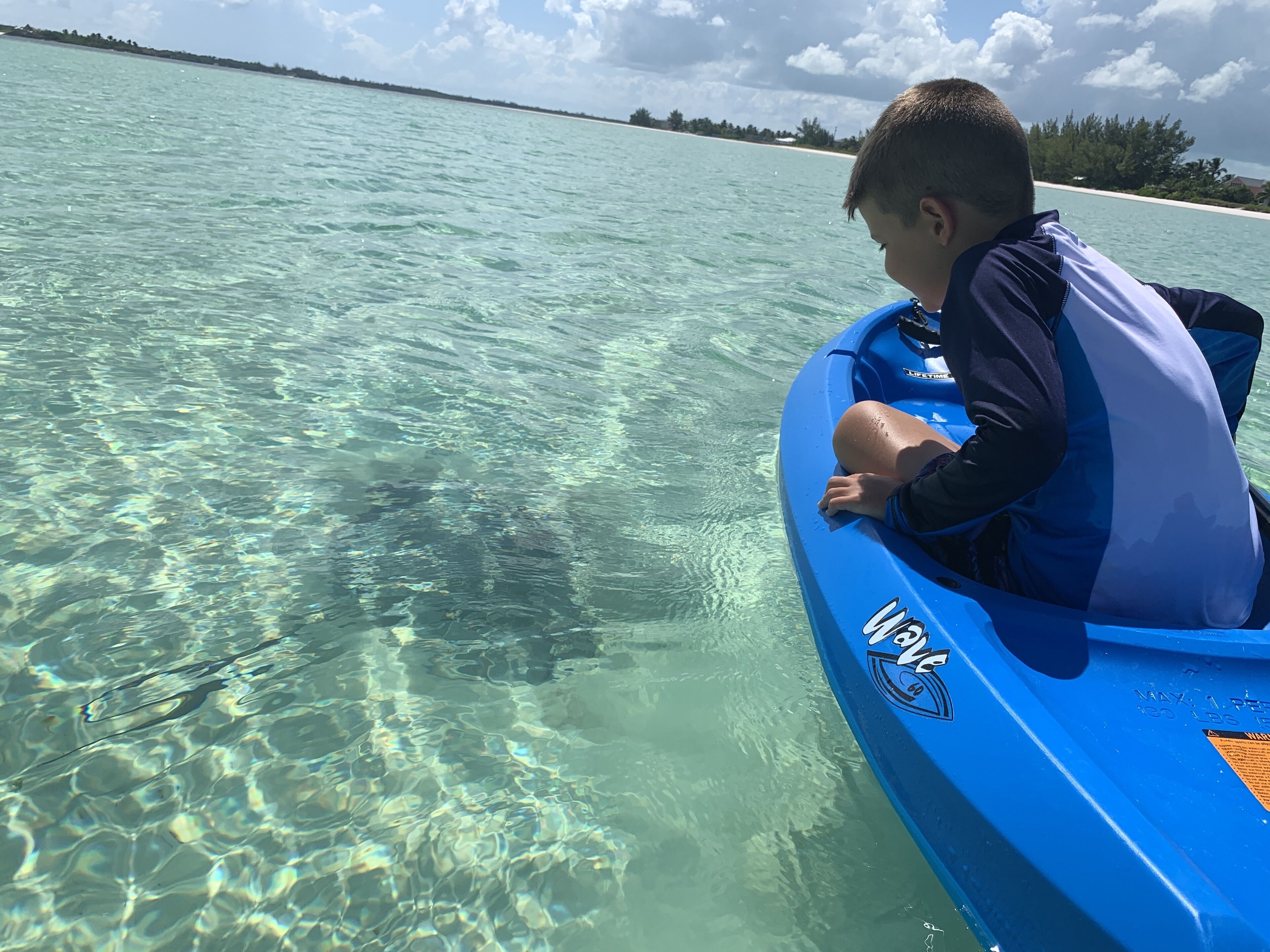 A person in a blue inflatable boat on clear turquoise water.