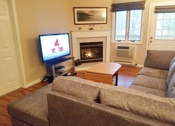 Ein Wohnzimmer mit Kamin, Fernseher und einer Couch.