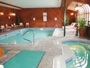 Ein Hallenschwimmbad mit Liegestühlen und einer Holzverkleidung.