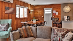 A cozy cabin interior with a wooden interior, a dining area, and a kitchen area.