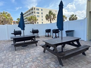 An outdoor patio area with picnic tables and barbecue grills. - Best Sunsets on the Beach! 3/3 between Clearwater & St. Pete, Anglers Cove # 107 (Redington Shores)