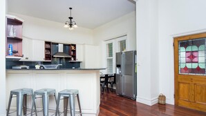 Eine moderne Küche mit weißen Schränken, einem Edelstahlkühlschrank und einer Bar mit Hockern.