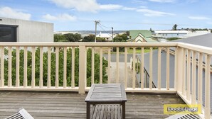 Eine Holzdielen-Terrasse mit Geländer, Tisch und Bank.