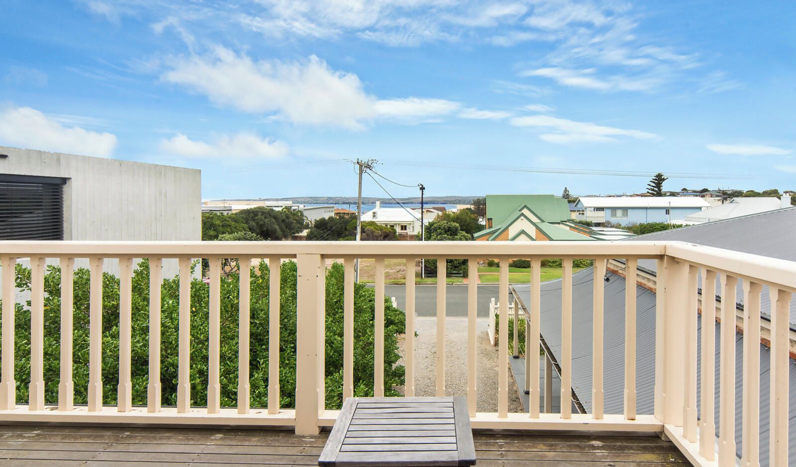 A wooden deck with a railing, a table, and a bench.